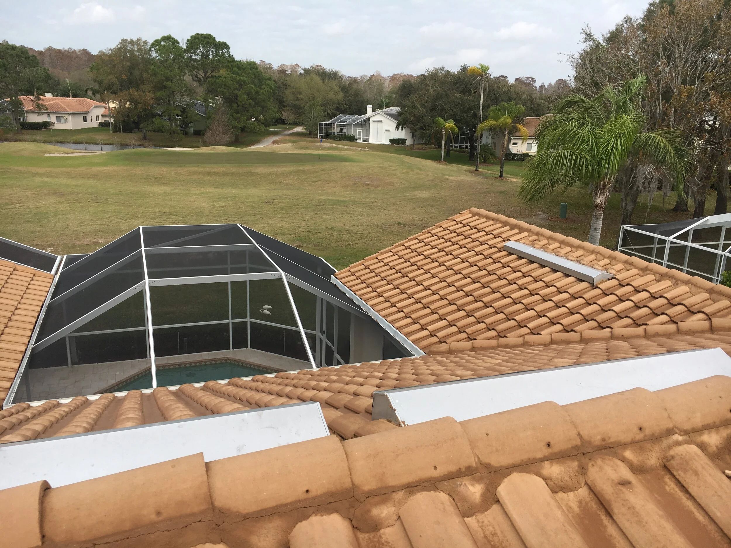Pool cage and screen enclosure beside a cleaned tile roof at Crescent Oaks