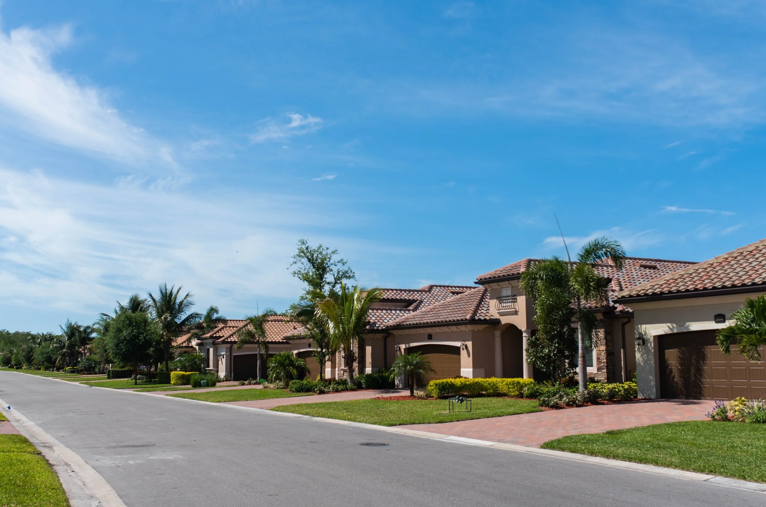 Street of tile-roof homes with paver driveways in a Florida residential community